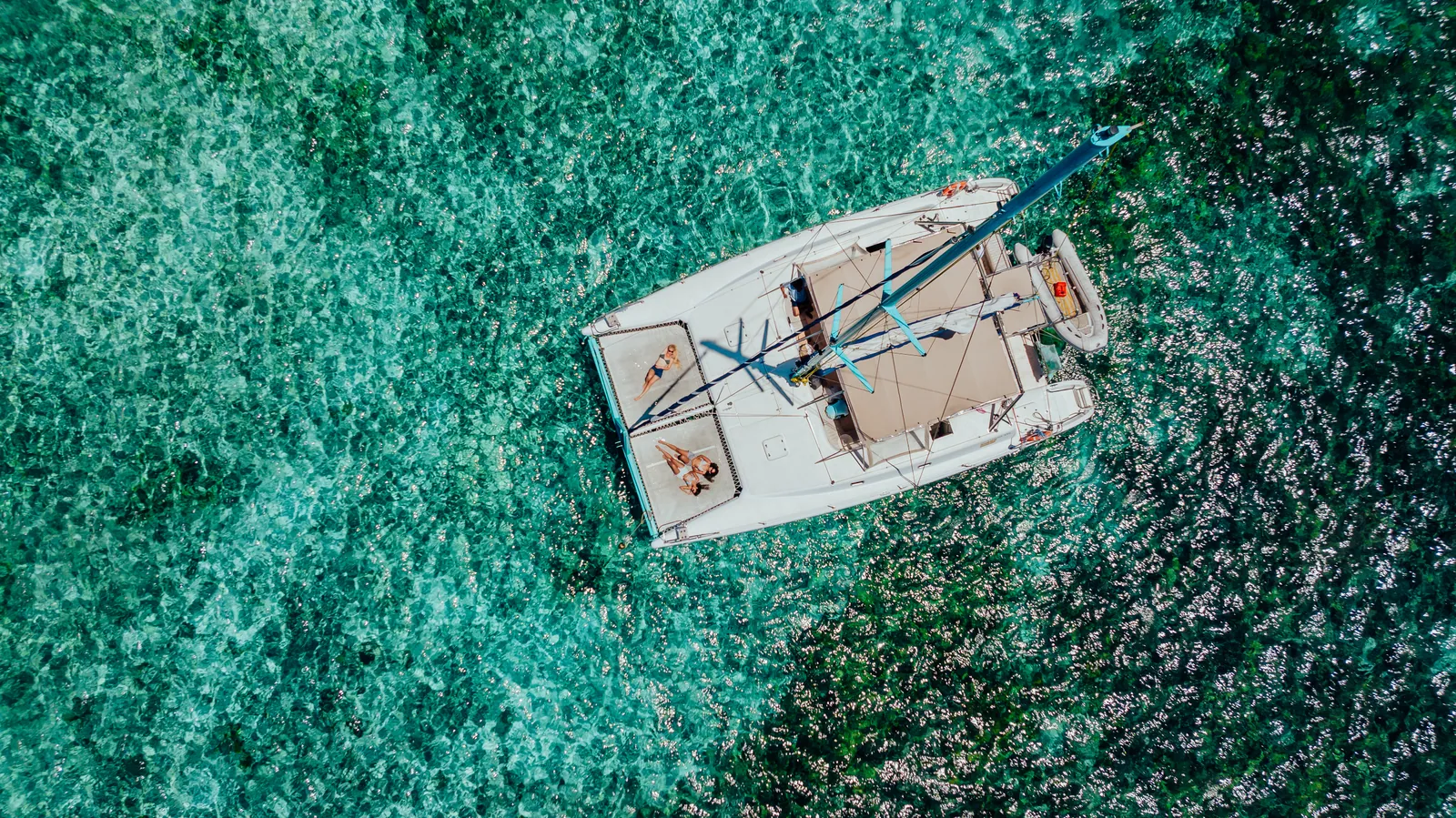 Overhead view of a catamaran surrounded by clear green-blue water.